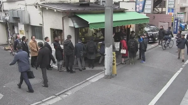 People lining up outside a small shop in Documentary 72 Hours.